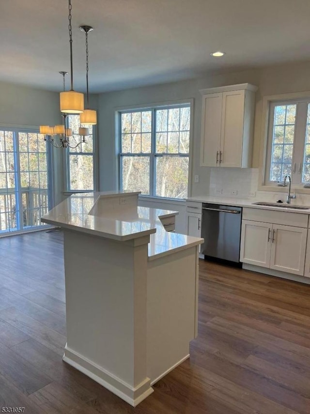 kitchen with white cabinets, sink, stainless steel dishwasher, decorative light fixtures, and a kitchen island