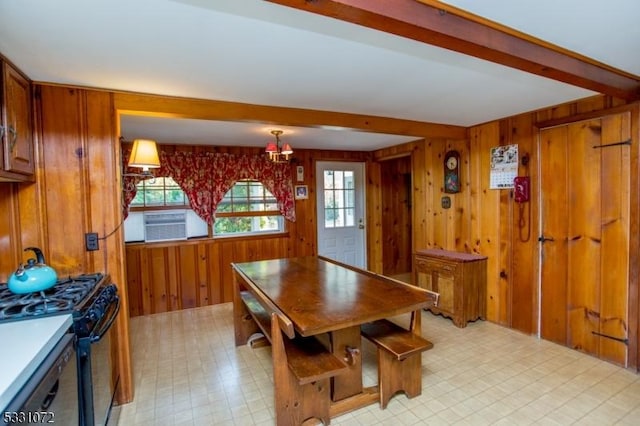 dining room with beam ceiling and wooden walls