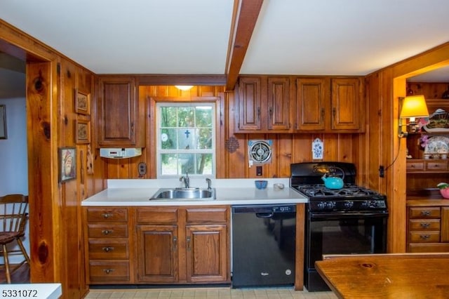 kitchen with beam ceiling, sink, wood walls, and black appliances