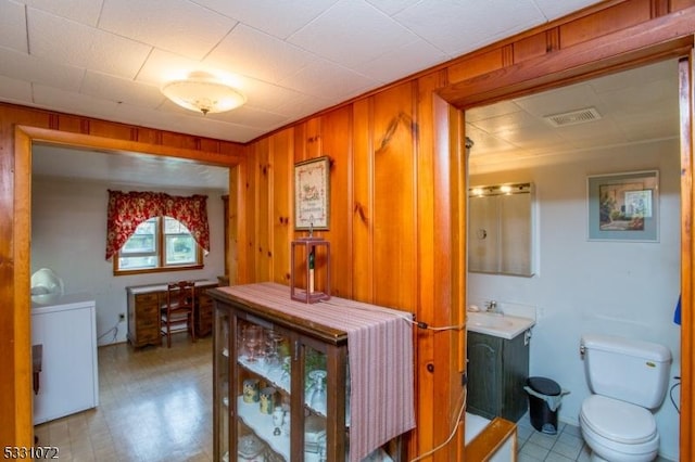 bathroom featuring wooden walls, vanity, and toilet