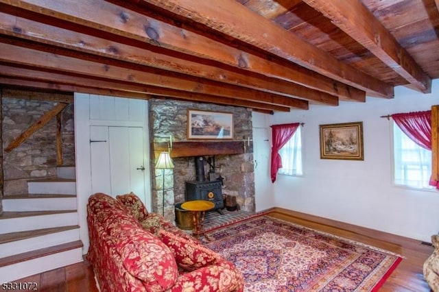 living room with beamed ceiling, a wood stove, and hardwood / wood-style flooring