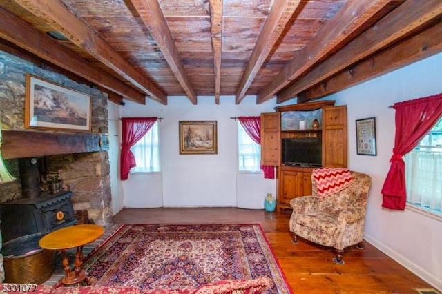 living room with beam ceiling, hardwood / wood-style flooring, a wood stove, and wood ceiling