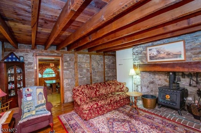 living room with hardwood / wood-style floors, beam ceiling, and a wood stove