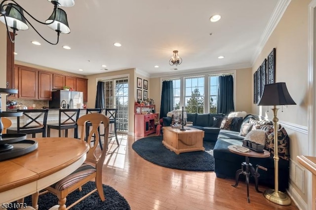 dining area featuring light hardwood / wood-style flooring, ornamental molding, and a notable chandelier