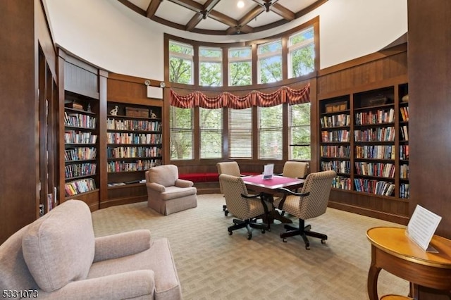 carpeted office space with a high ceiling, coffered ceiling, wooden walls, built in features, and beam ceiling