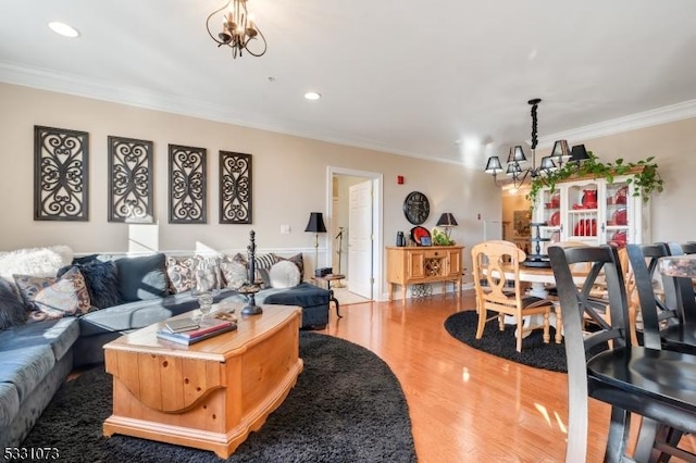 living room with wood-type flooring, crown molding, and a notable chandelier