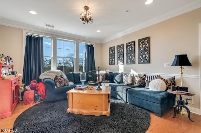 living room featuring crown molding, light hardwood / wood-style flooring, and an inviting chandelier