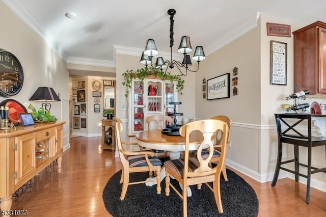 dining area featuring light hardwood / wood-style flooring, an inviting chandelier, and ornamental molding