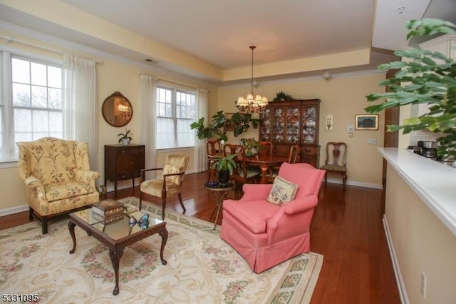 living area featuring a tray ceiling, crown molding, a chandelier, and dark hardwood / wood-style floors