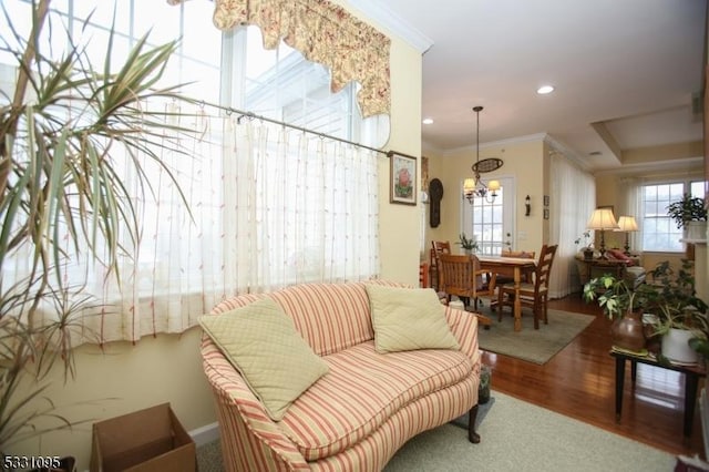 living room with hardwood / wood-style flooring, a notable chandelier, and ornamental molding