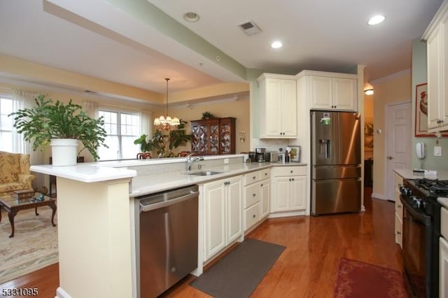 kitchen with pendant lighting, an inviting chandelier, sink, appliances with stainless steel finishes, and kitchen peninsula