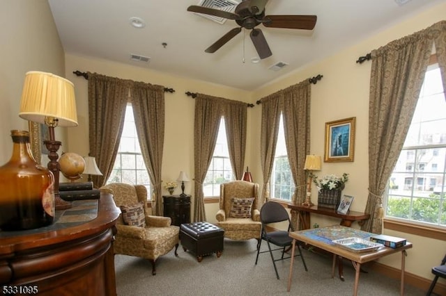 living area featuring a wealth of natural light, carpet floors, and ceiling fan