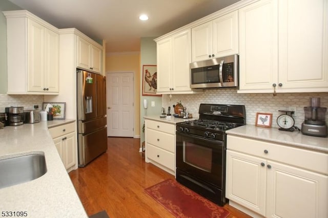 kitchen with white cabinets, hardwood / wood-style floors, backsplash, and stainless steel appliances