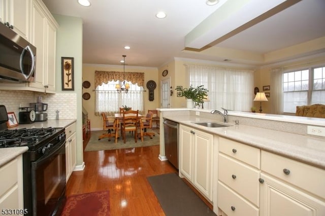 kitchen featuring decorative backsplash, appliances with stainless steel finishes, dark hardwood / wood-style flooring, sink, and hanging light fixtures