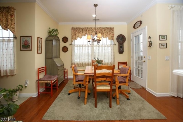 dining area with a healthy amount of sunlight, dark hardwood / wood-style flooring, ornamental molding, and an inviting chandelier