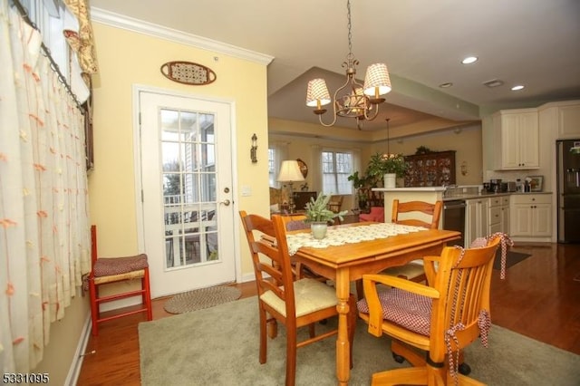 dining space featuring dark hardwood / wood-style flooring, ornamental molding, and an inviting chandelier