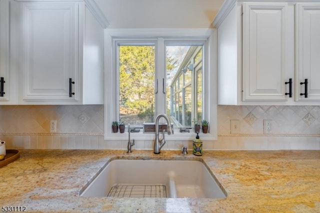 kitchen featuring sink, tasteful backsplash, white cabinetry, and light stone countertops