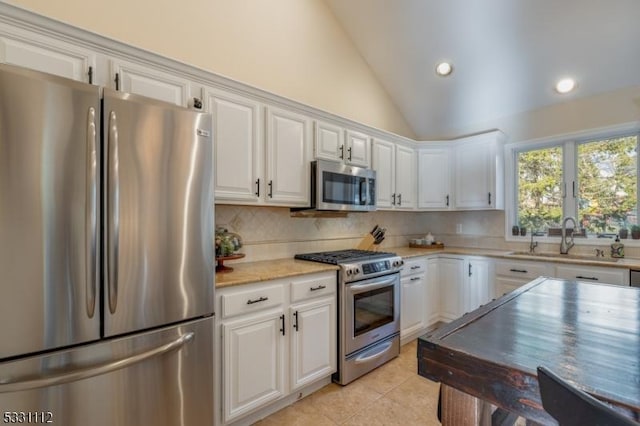 kitchen featuring stainless steel appliances, light tile patterned floors, backsplash, white cabinets, and sink