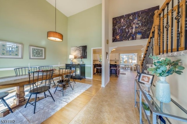 dining room featuring high vaulted ceiling and light tile patterned flooring