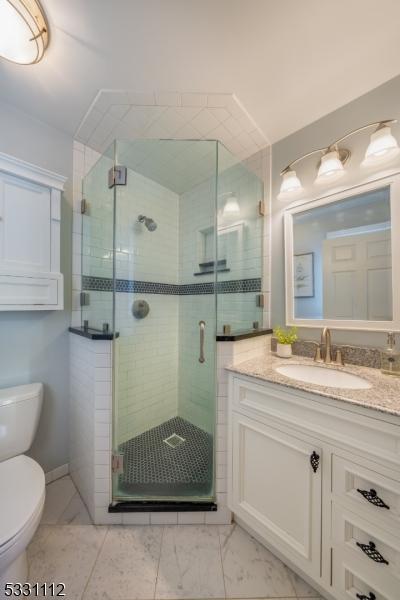 bathroom with toilet, a shower with door, and vanity