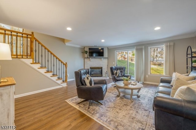 living room featuring a fireplace, ornamental molding, and hardwood / wood-style floors