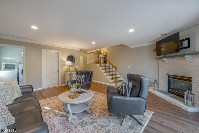 living room featuring hardwood / wood-style flooring, ornamental molding, separate washer and dryer, and a fireplace