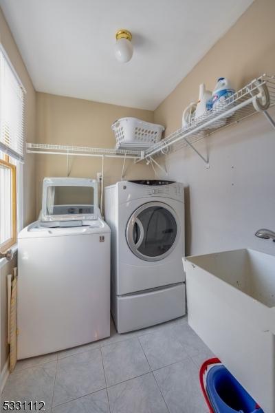 laundry room featuring washer and dryer, sink, and light tile patterned floors