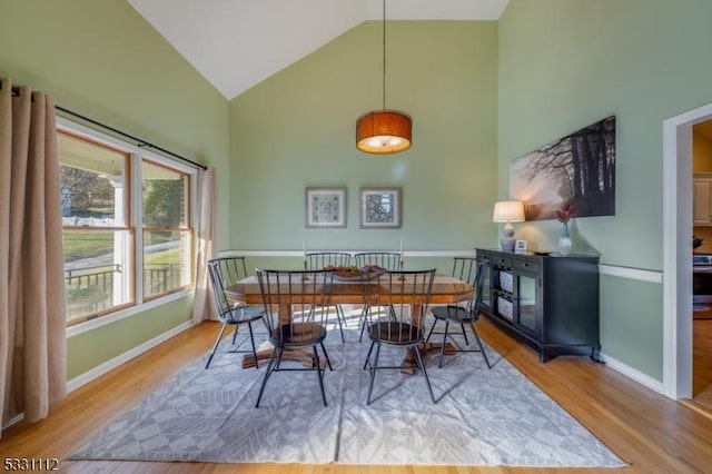 dining area with high vaulted ceiling and light wood-type flooring