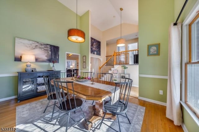 dining area with light wood-type flooring and high vaulted ceiling