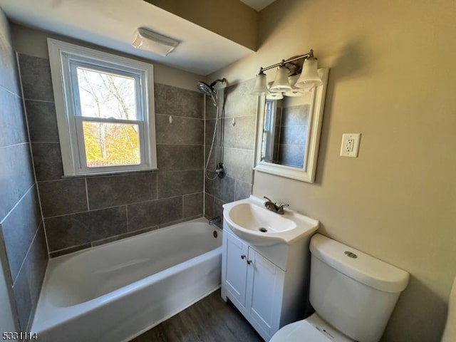 full bathroom featuring vanity, wood-type flooring, tiled shower / bath combo, and toilet