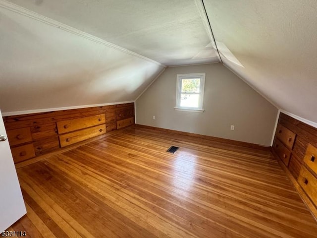 additional living space with a textured ceiling, light hardwood / wood-style floors, and vaulted ceiling