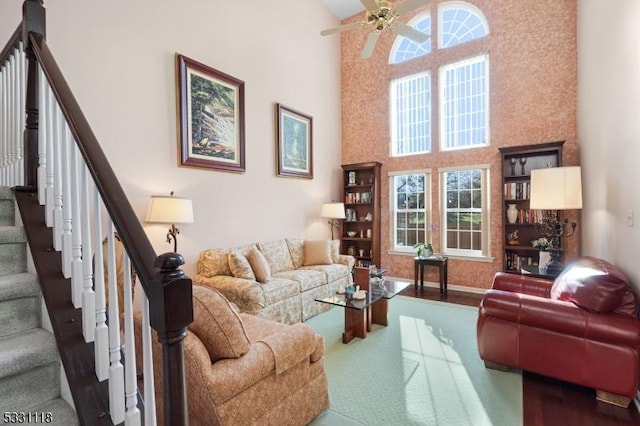 living room with ceiling fan and a towering ceiling