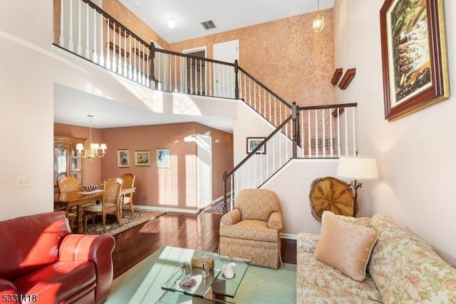 living room with a towering ceiling, hardwood / wood-style flooring, and a notable chandelier