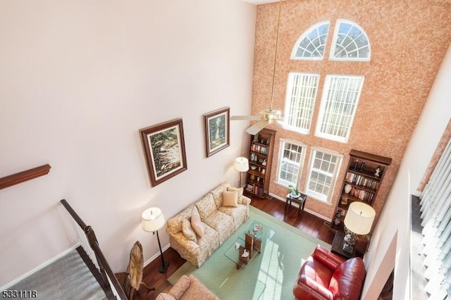 living room with a towering ceiling and dark wood-type flooring