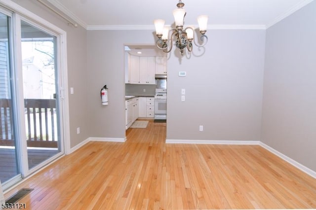 unfurnished dining area with light hardwood / wood-style floors, an inviting chandelier, and crown molding