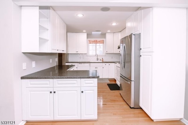 kitchen with white cabinets, stainless steel fridge, kitchen peninsula, and sink