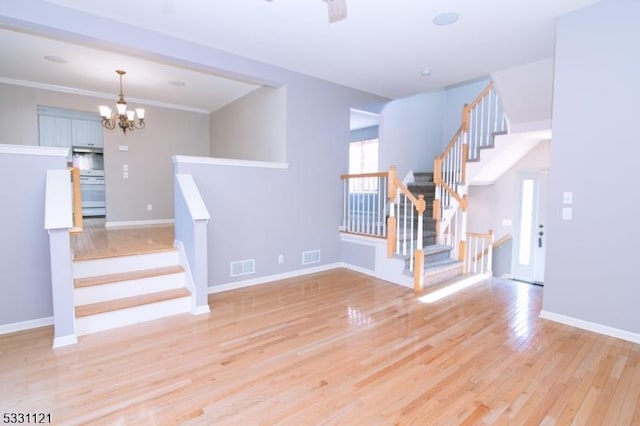 interior space featuring hardwood / wood-style flooring, crown molding, and a notable chandelier