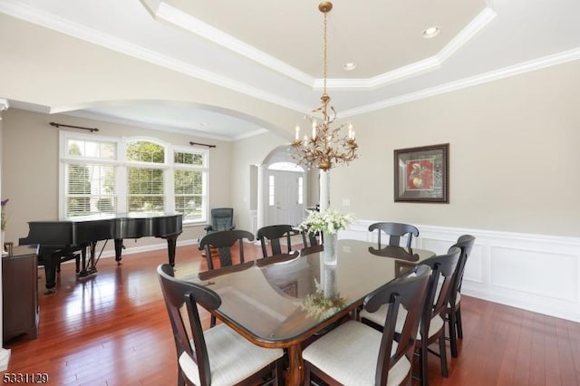 dining area with a chandelier, a raised ceiling, and crown molding