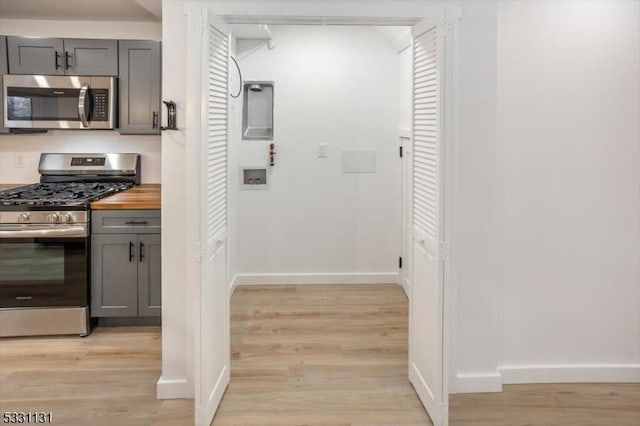 kitchen featuring stainless steel appliances, light hardwood / wood-style flooring, butcher block counters, and gray cabinetry