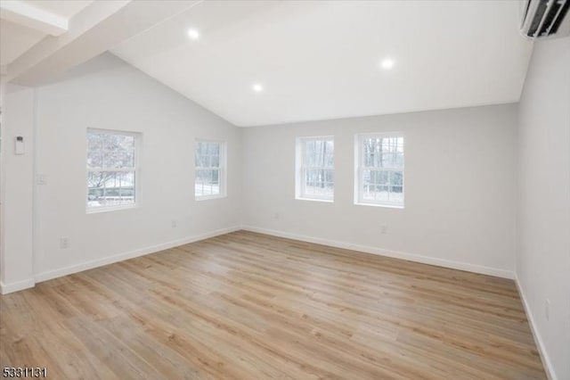 spare room with lofted ceiling with beams, a wall mounted air conditioner, and light wood-type flooring