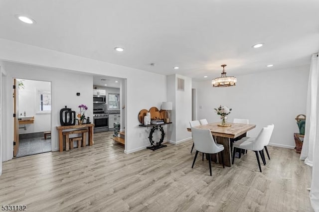 dining space featuring light hardwood / wood-style floors and an inviting chandelier