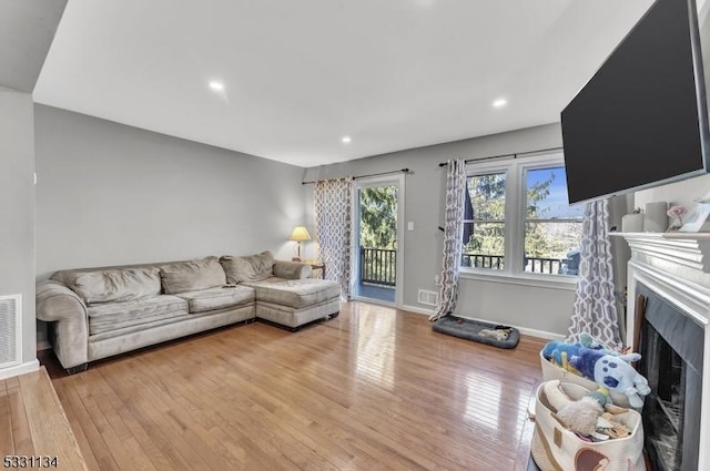 living area with a fireplace, recessed lighting, visible vents, light wood-type flooring, and baseboards