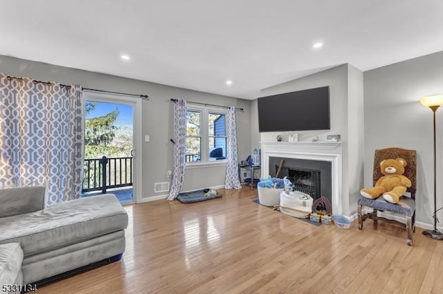 living room featuring a fireplace, baseboards, and wood finished floors