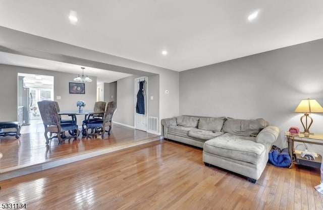 living area featuring baseboards, visible vents, a notable chandelier, and hardwood / wood-style floors