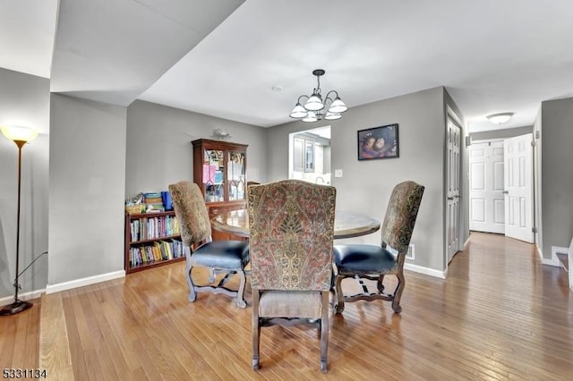 dining room featuring an inviting chandelier, hardwood / wood-style flooring, and baseboards