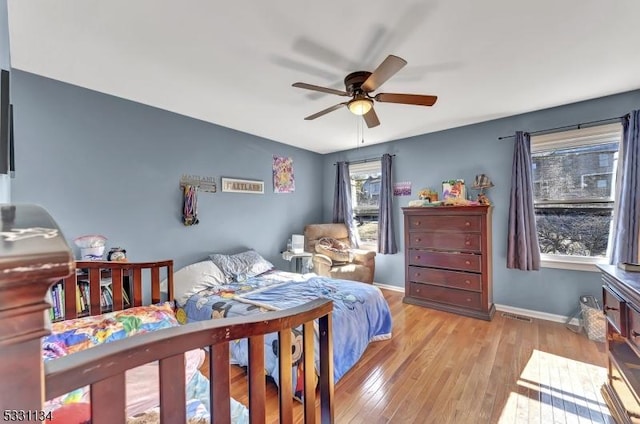 bedroom with a ceiling fan, visible vents, baseboards, and hardwood / wood-style flooring