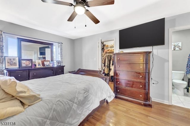 bedroom featuring a ceiling fan, wood finished floors, ensuite bathroom, a walk in closet, and a closet