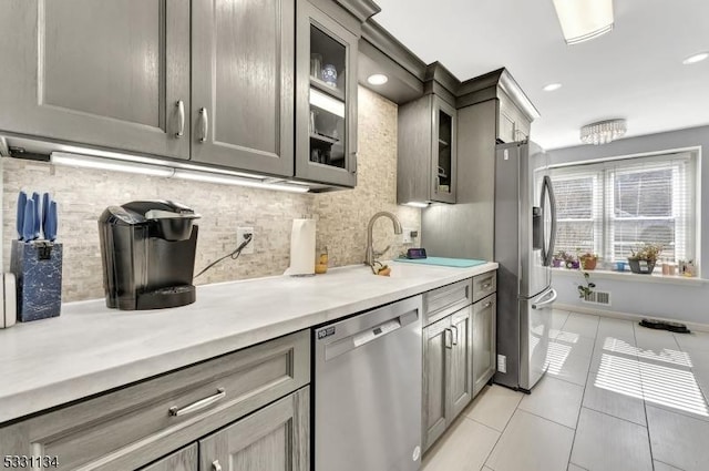 kitchen with light tile patterned floors, stainless steel appliances, and gray cabinetry