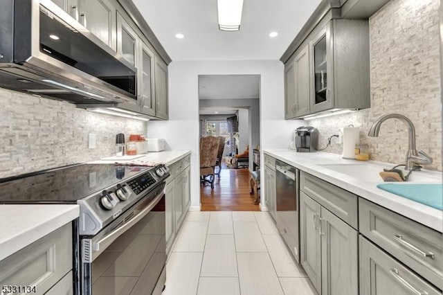 kitchen with appliances with stainless steel finishes, light countertops, and gray cabinetry