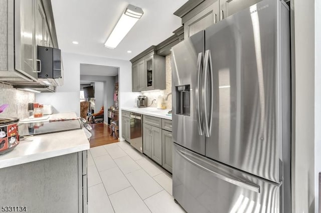 kitchen featuring light countertops, appliances with stainless steel finishes, gray cabinets, and decorative backsplash